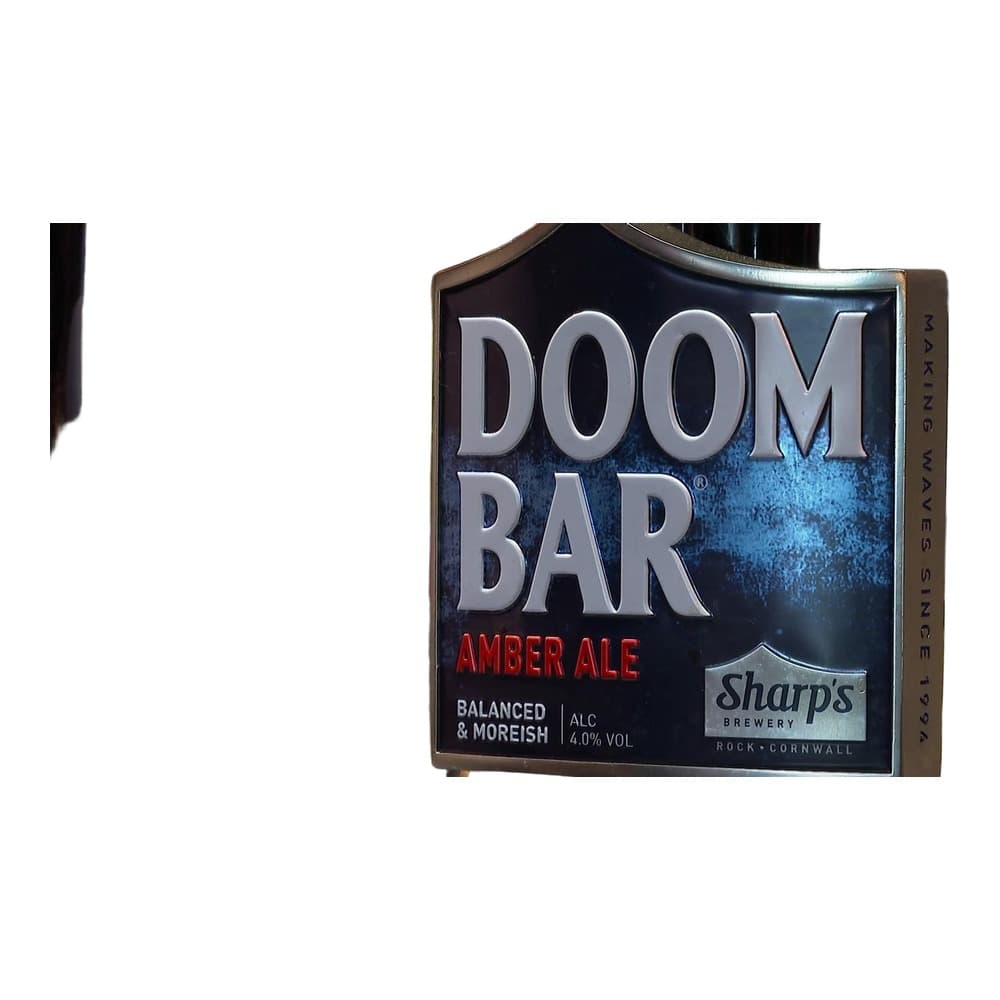 A Doom Bar Amber Ale pump clip from Sharp's Brewery displayed at a bar, with a pint glass and garden foliage visible in the background.