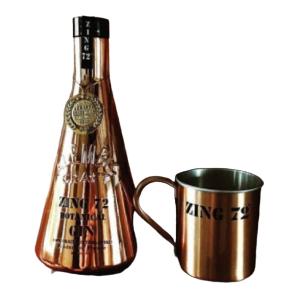 A copper-coloured spirits bottle with decorative label and a stainless steel mug with matching branding, displayed against an aged brick wall background