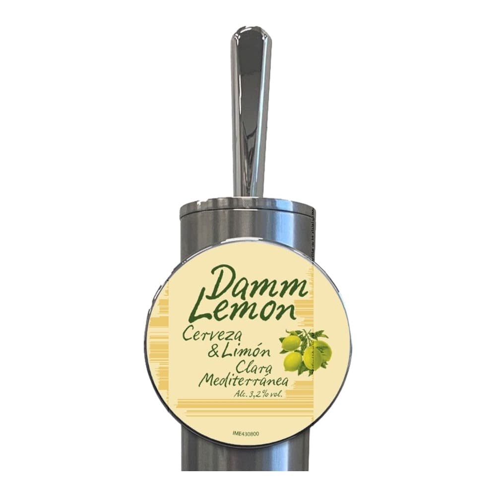 A metallic silver bottle with a cream-coloured circular label for Damm Lemon beer, featuring the product name and imagery of lemon and hops against a white background.