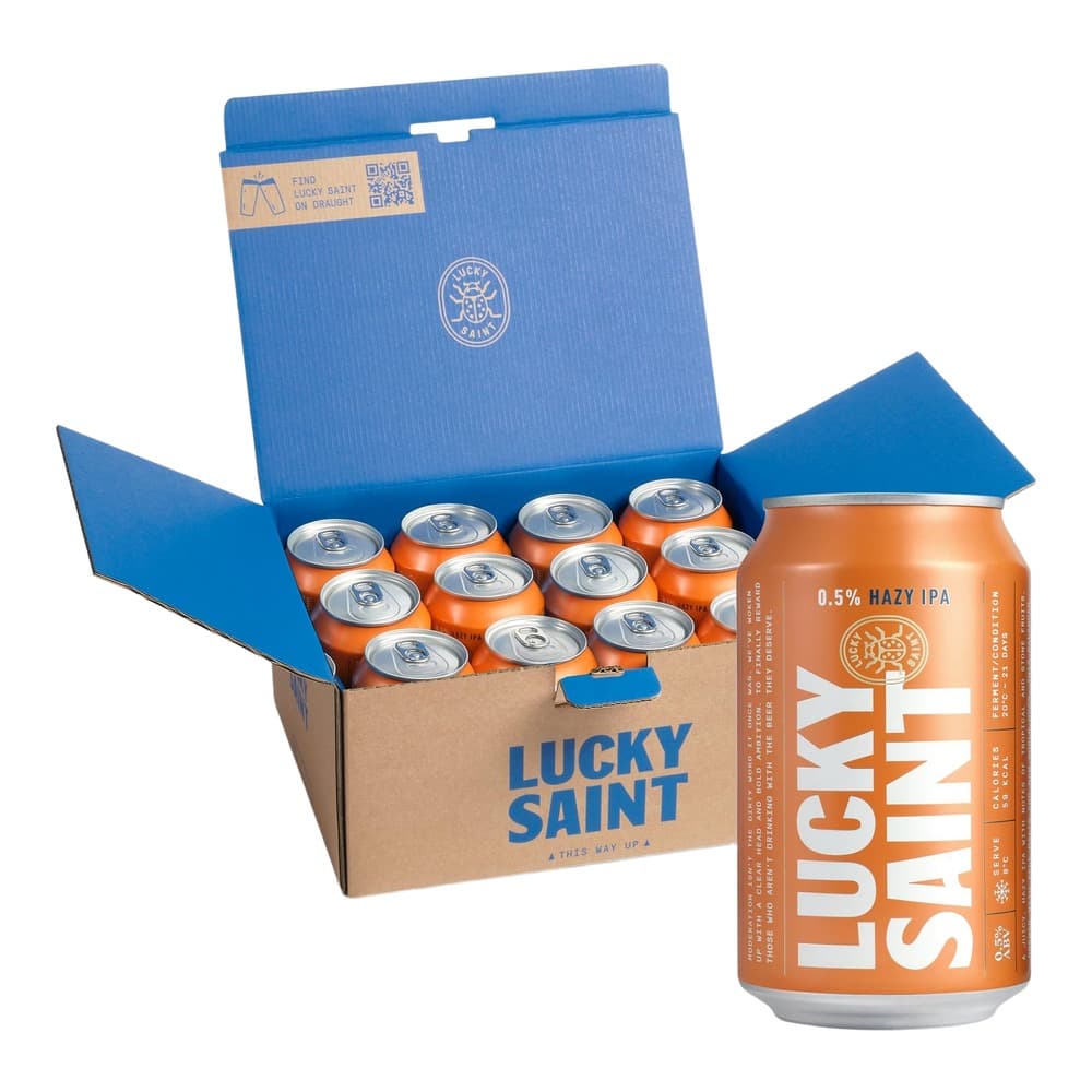 Orange Lucky Saint Hazy IPA beer can displayed next to an open cardboard box containing multiple orange beer cans with blue lid packaging.