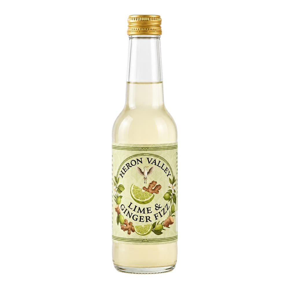 A clear glass bottle of Heron Valley Lime & Ginger Fizz with a gold screw cap, featuring a cream and green label with illustrations of lime slices and ginger root, containing pale yellow liquid, isolated on a white background.