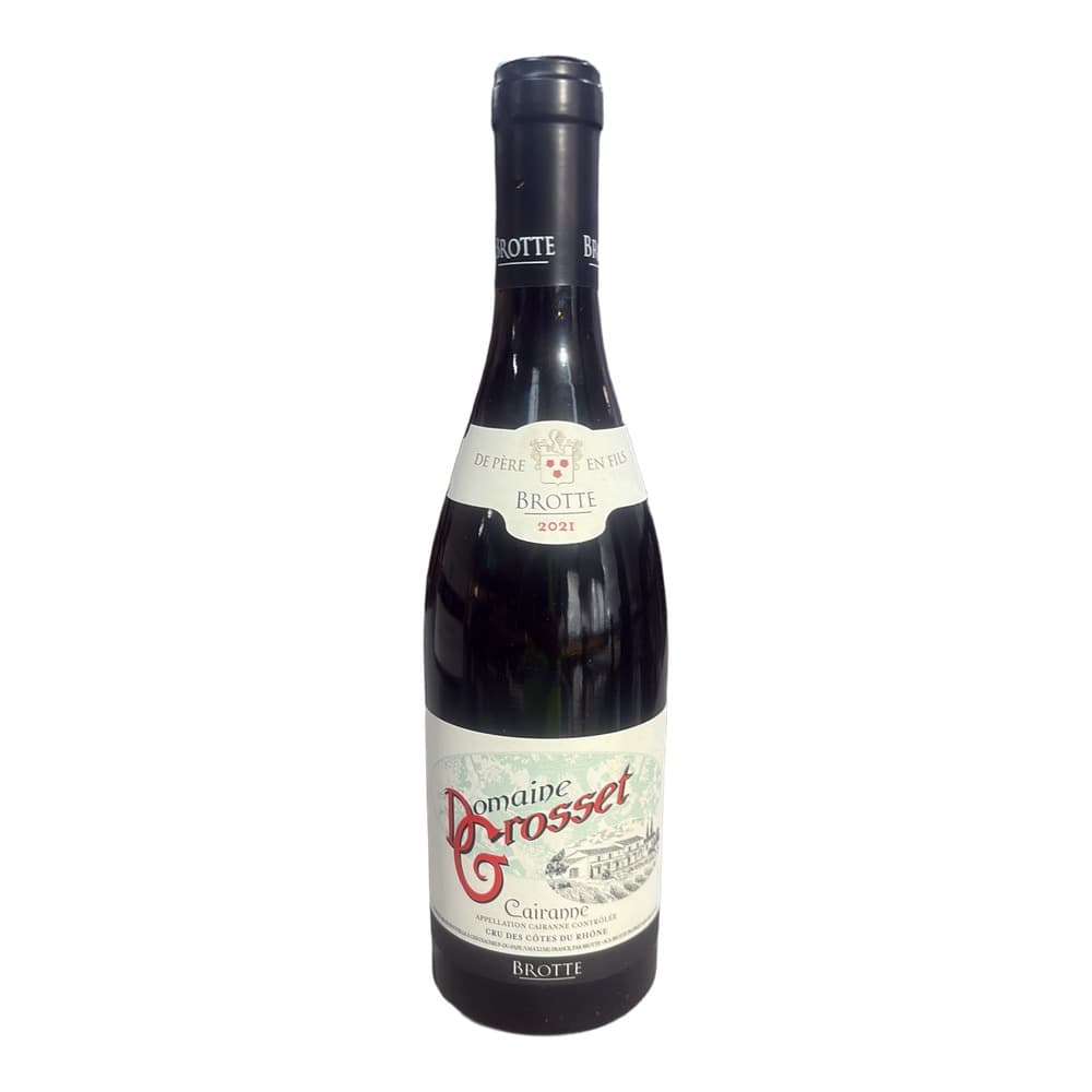 A bottle of Domaine Grosset Cairanne 2021 red wine with white label displayed on a light surface against an industrial background.