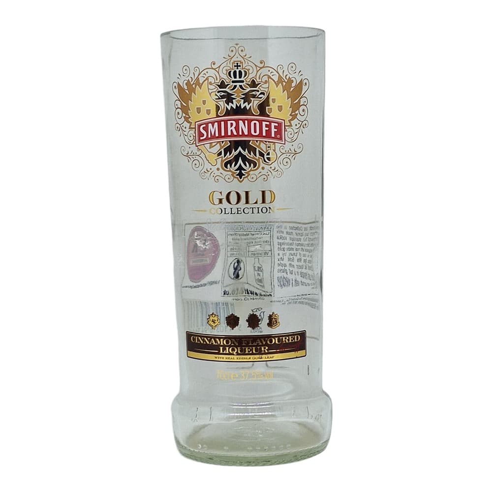 A clear glass bottle of Smirnoff Gold Collection Cinnamon Flavoured Liqueur featuring the brand's ornate emblem and crest on a plain grey background.