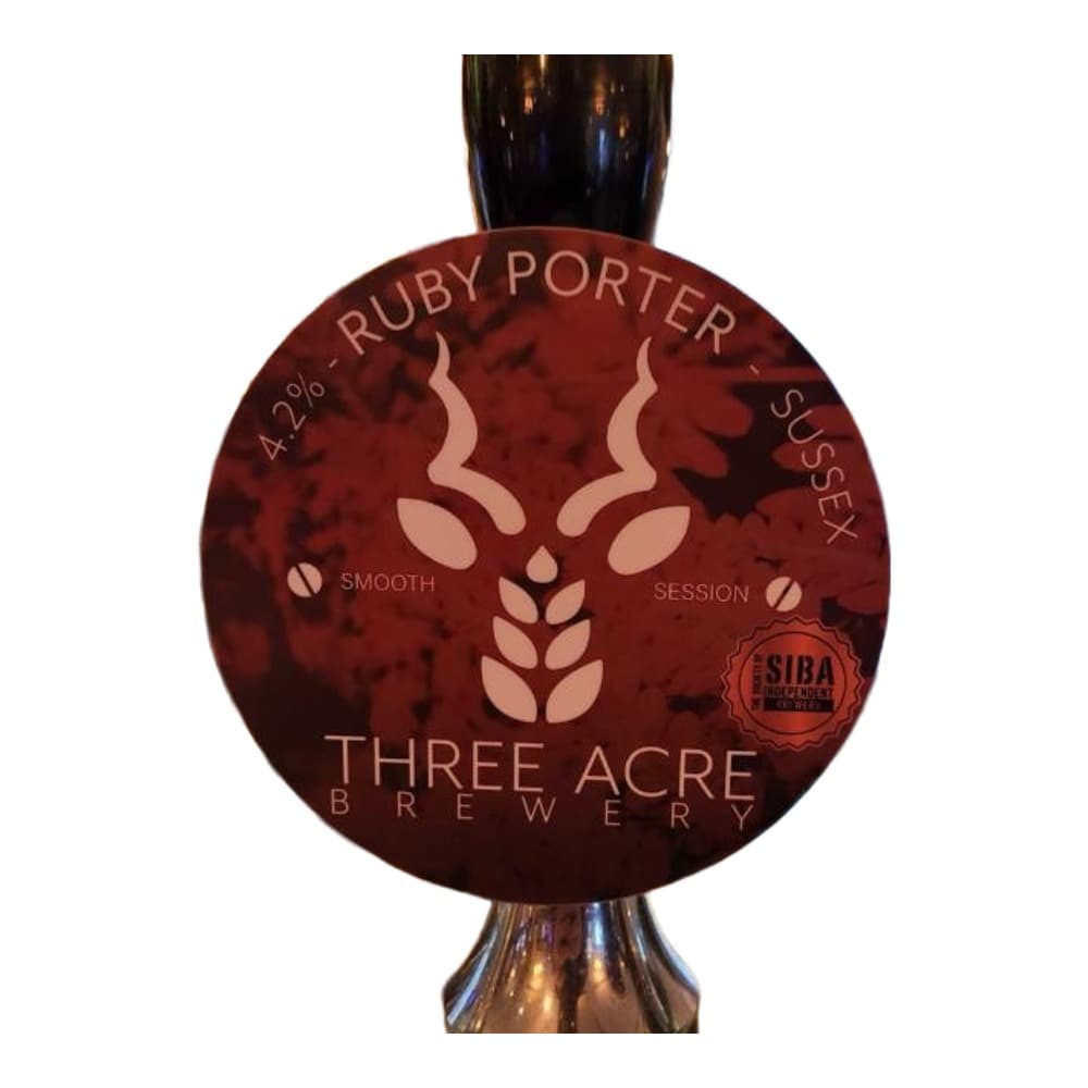 A beer pump clip for Three Acre Brewery's Ruby Porter displayed in a pub setting with bar shelving and bottles visible in the background.