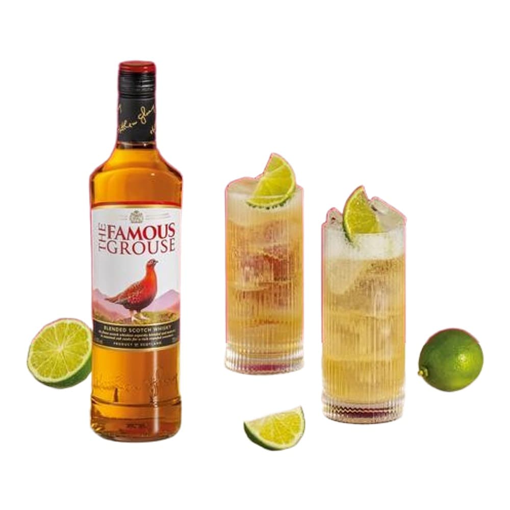 A bottle of The Famous Grouse whisky displayed alongside two mixed cocktails garnished with lime wedges on a neutral background, with fresh lime slices scattered around.