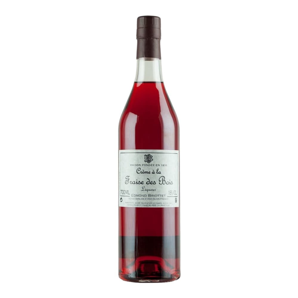 A bottle of Crème à la Fraise des Bois liqueur with a deep burgundy red liquid, cream-coloured label, and dark cork stopper, isolated on a white background.