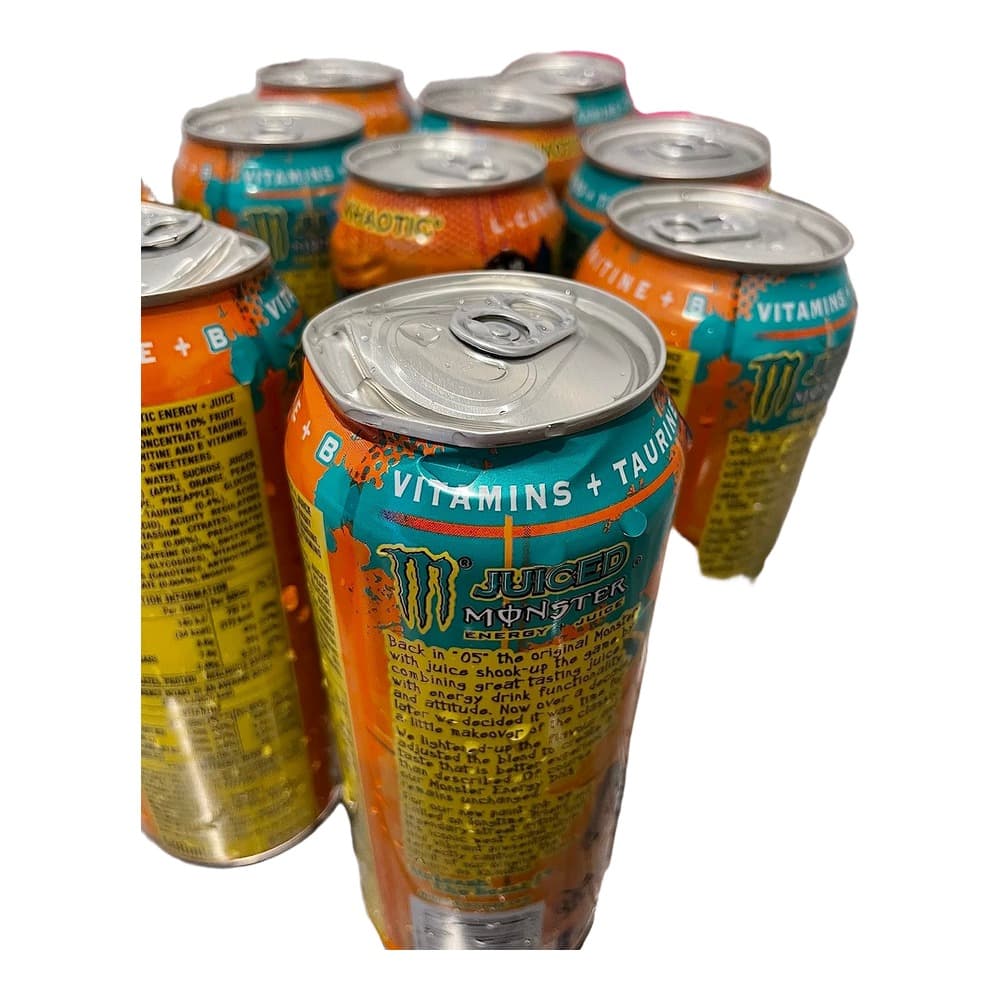 Multiple opened and unopened cans of Monster Energy Juiced drink displayed on a white surface, showing orange and teal branded packaging with visible pull-tab tops.