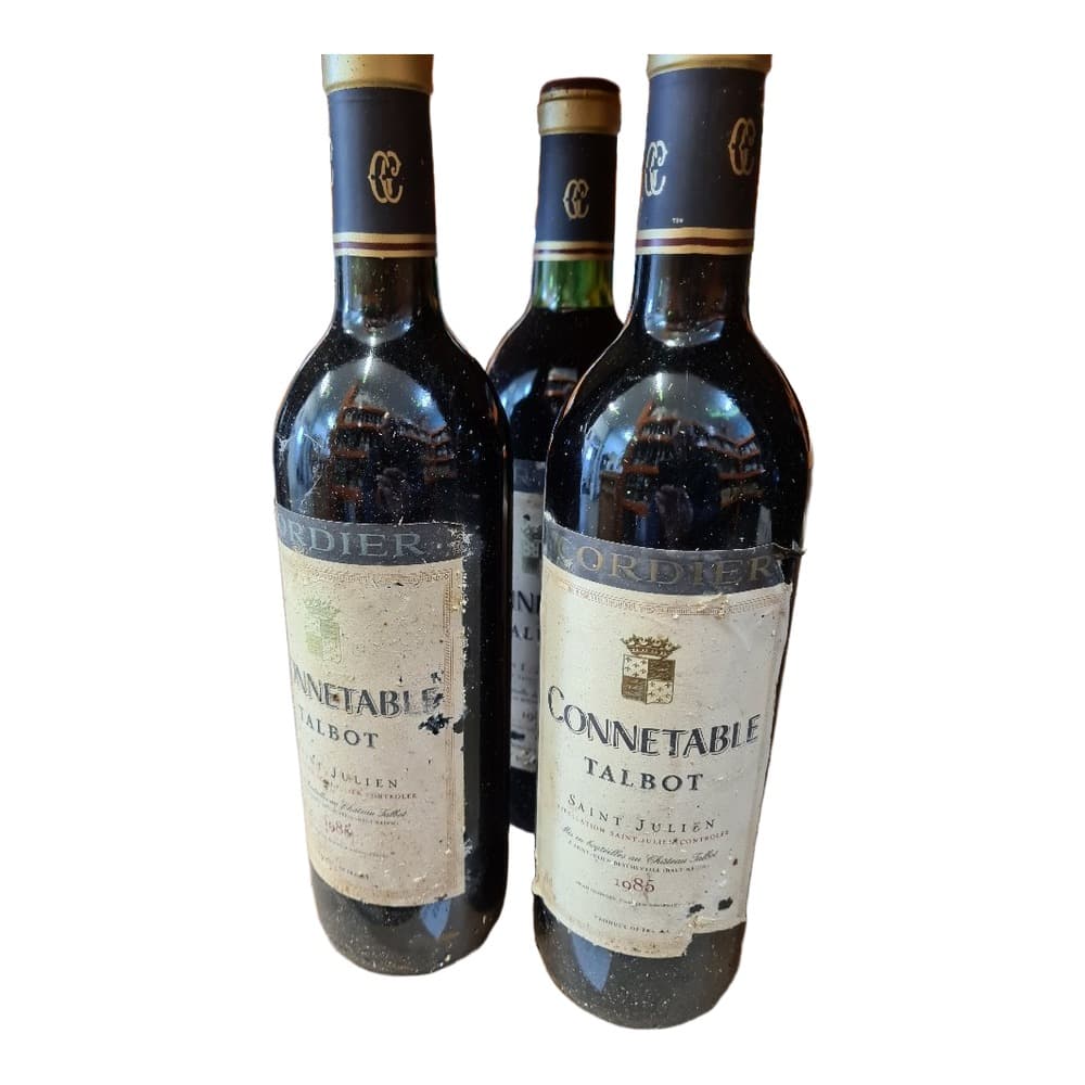 Three bottles of Connetable Talbot Saint-Julien red wine with navy blue and gold labels displayed on a wooden surface.