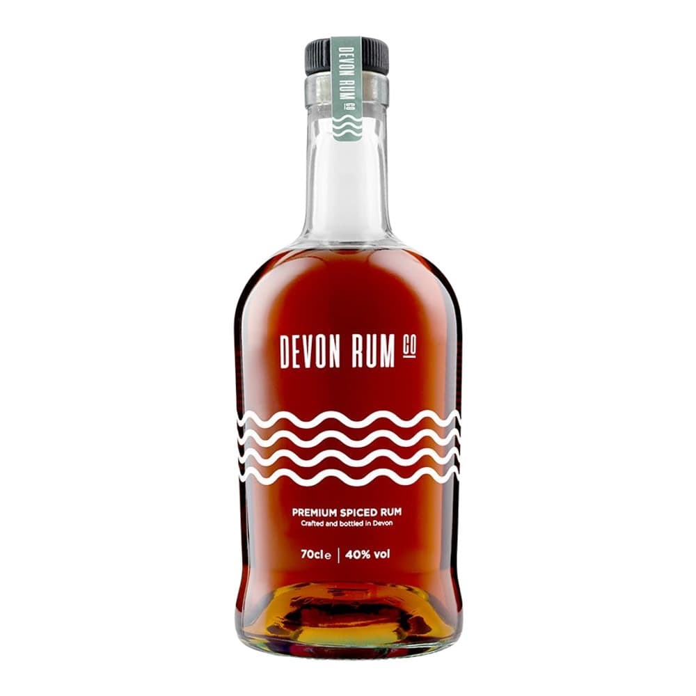 A bottle of Devon Rum Co premium spiced rum with dark amber liquid, featuring a grey and black cap with wavy water-inspired label design on a white background.