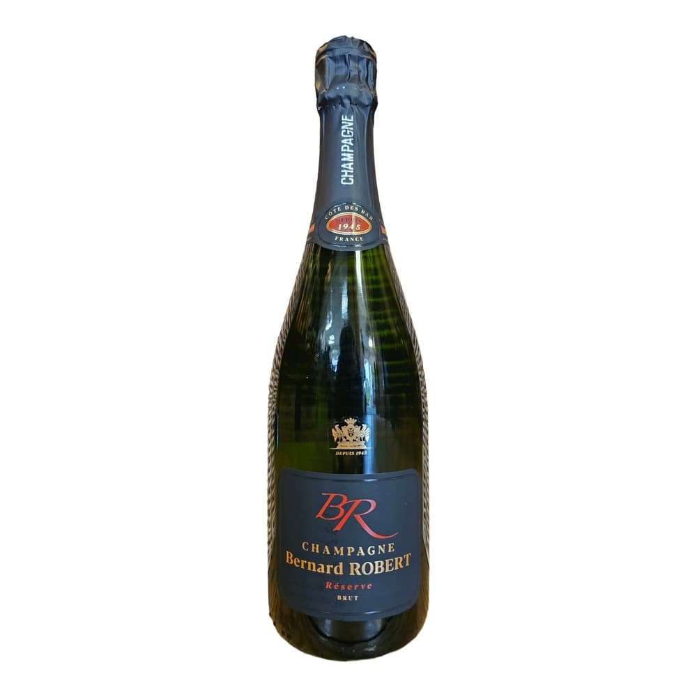 A bottle of Bernard Robert Champagne Réserve Brut displayed against a woven wicker basket background on a wooden surface.