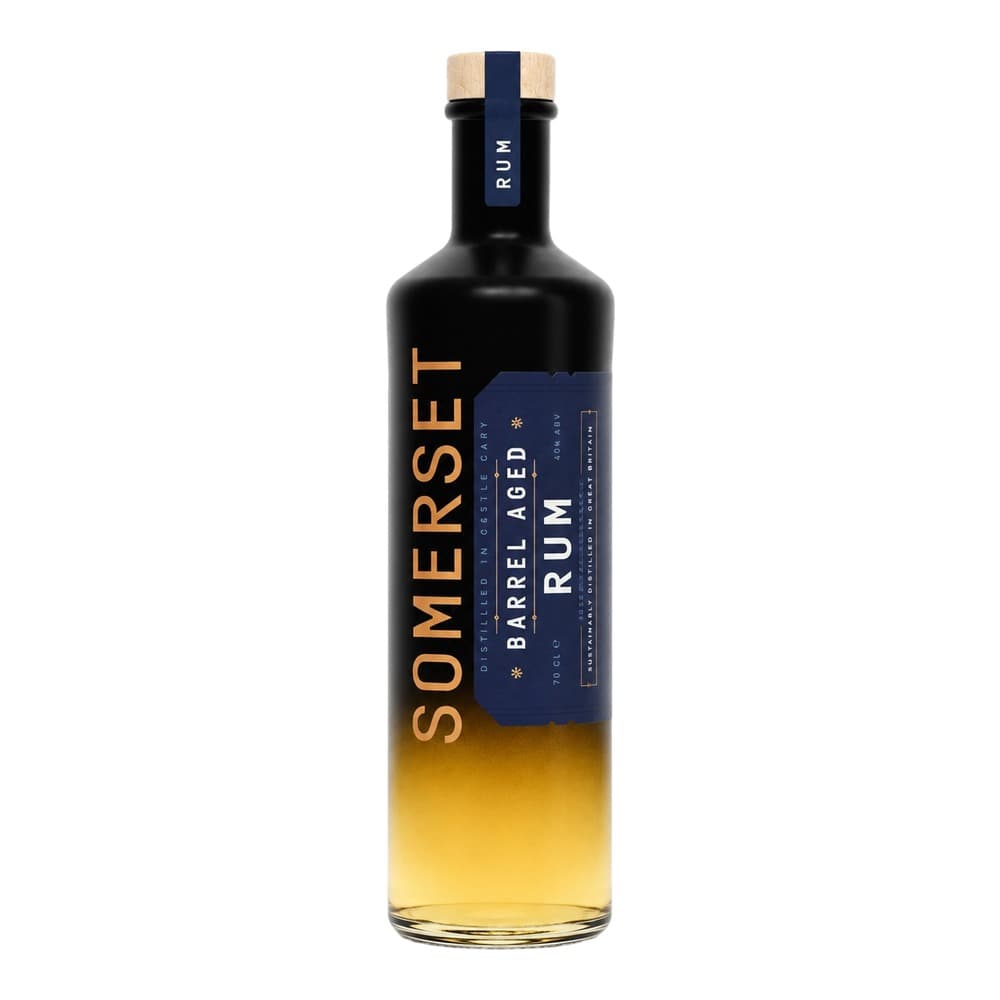 A bottle of Somersét barrel aged rum with a black glass body and wooden cork stopper, featuring a dark blue label with gold lettering, displayed against a white background.